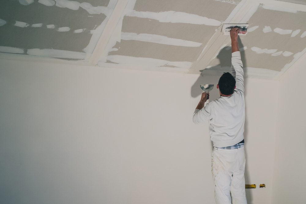 Applying skim coat to drywall ceiling